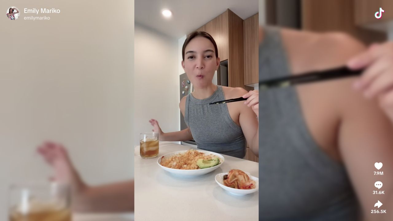 Emily Mariko eating the finished salmon-and-rice bowl with chopsticks, with kimchi on the counter.